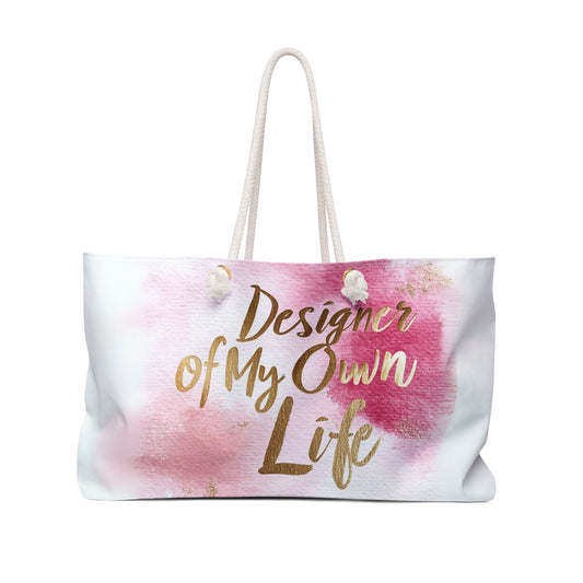 "DUO MODERN 'Designer of My Own Life' Weekender Tote in pink blush with gold font. Perfect for the modern jet-setter, combining elegance and practicality. Ideal for beach trips, luxe getaways, or city exploration."